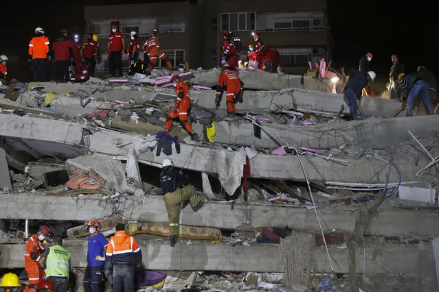 Members of rescue services search in the debris of a collapsed building for survivors in Izmir, Turkey, early Saturday, October 31, 2020. A strong earthquake struck Friday in the Aegean Sea between the Turkish coast and the Greek island of Samos, killing several people and injuring hundreds amid collapsed buildings and flooding. (Photo by Emrah Gurel/AP Photo)