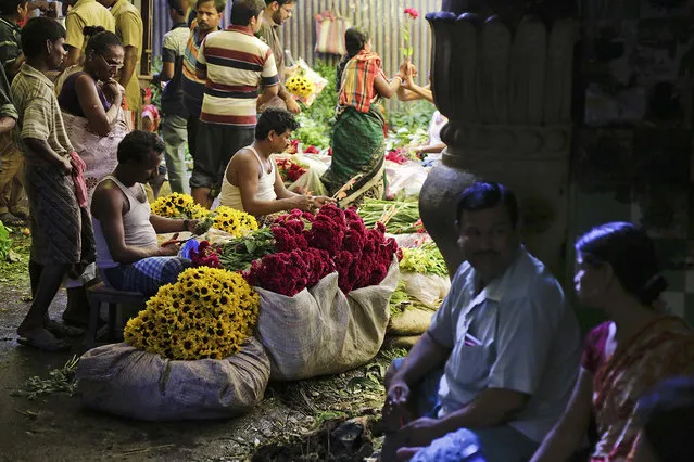 Indians buy flowers from a wholesale market during Durga Puja Hindu festival in Kolkata, India, Sunday, October 9, 2016. The five-day festival commemorates the slaying of a demon king by goddess Durga, marking the triumph of good over evil. (Photo by Bikas Das/AP Photo)