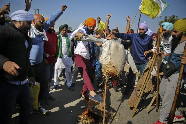 Protesting farmers burn an effigy of Indian Prime Minister Narendra Modi on a highway, refusing to move ahead unless they're allowed to proceed to their place of choice to protest, at the Delhi-Haryana state border, India, Saturday, November 28, 2020. Thousands of farmers in and around the Indian capital on Saturday pressed on with their protest against agricultural legislation they said could devastate crop prices, while the government sought talks with their leaders. (Photo by Altaf Qadri/AP Photo)