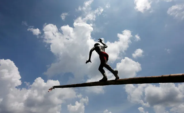 A boy climbs up a greasy pole in a climbing competition at a part of Sinhala, the Hindu and Tamil New Year celebrations, in Bandaragama, Sri Lanka April 21, 2018. (Photo by Dinuka Liyanawatte/Reuters)