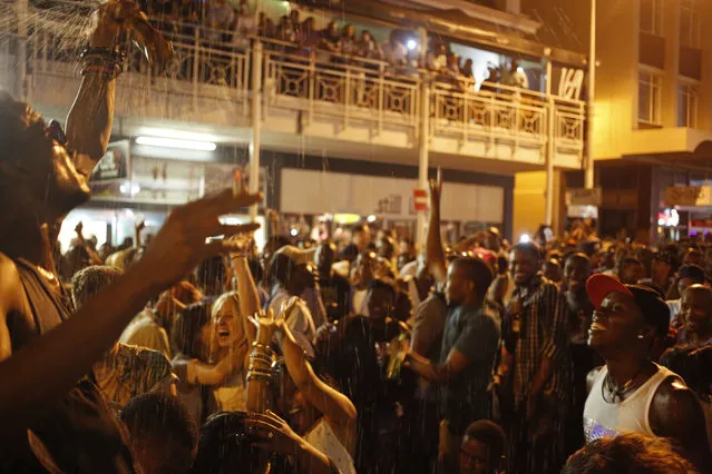 A man sprays his drink over people as they  celebrate the New Year in a main party zone in the city of Cape Town, South Africa, Thursday, January 1, 2015. (Photo by Schalk van Zuydam/AP Photo)