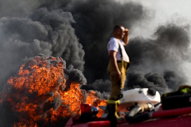A firefighter looks on as smoke and fire billows at the Zubair oil field in in southern Iraq on October 26, 2025. One person was killed and at least nine others were injured on October 26 in a fire caused by a gas leak in one of the systems at an oil field in southern Iraq, according to an initial toll announced by the authorities. (Photo by Hussein Faleh/AFP Photo)
