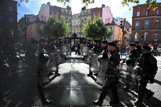 French Republican Security Corps (CRS - Compagnies Republicaines de Securite) police officers, reflected on an advertisement board, walk towards demonstrators during a demonstration in Toulouse, on October 2, 2025, as part of a nation-wide day of strike called by France's eight biggest workers unions for “social justice” measures. (Photo by Lionel Bonaventure/AFP Photo)