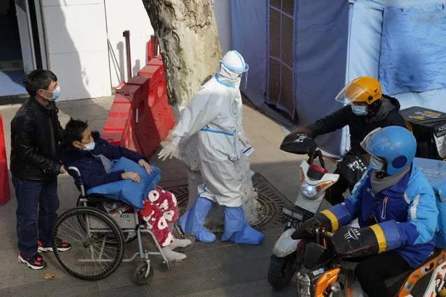 A medical worker in protector overall escorts a patient in wheelchair from the fever screening department of the Tongji Hospital which was at the frontline of the China's fight against the coronavirus in Wuhan in central China's Hubei province on Friday, January 15, 2021. The WHO team of international researchers that arrived in the central Chinese city of Wuhan on Thursday hopes to find clues to the origin of the COVID-19 pandemic. (Photo by Ng Han Guan/AP Photo)