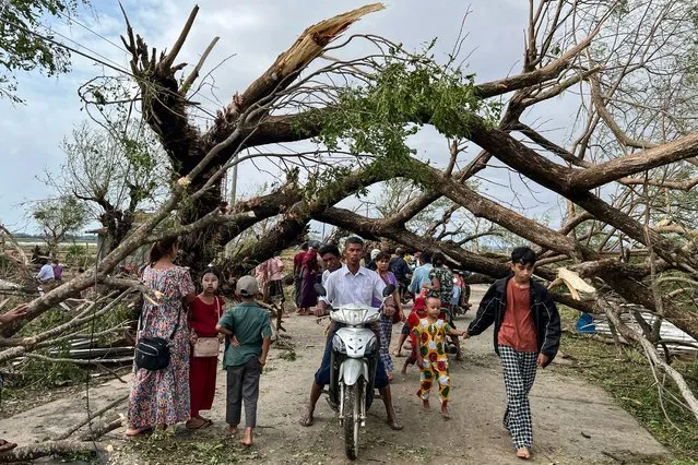 Residents walk past fallen trees in Kyauktaw in Myanmar's Rakhine state on May 15, 2023, after Cyclone Mocha crashed ashore. Cyclone Mocha crashed ashore in Myanmar and southeastern Bangladesh on May 14, uprooting trees, scattering flimsy homes in Rohingya displacement camps and bringing a storm surge into low-lying areas. (Photo by Sai Aung Main/AFP Photo)