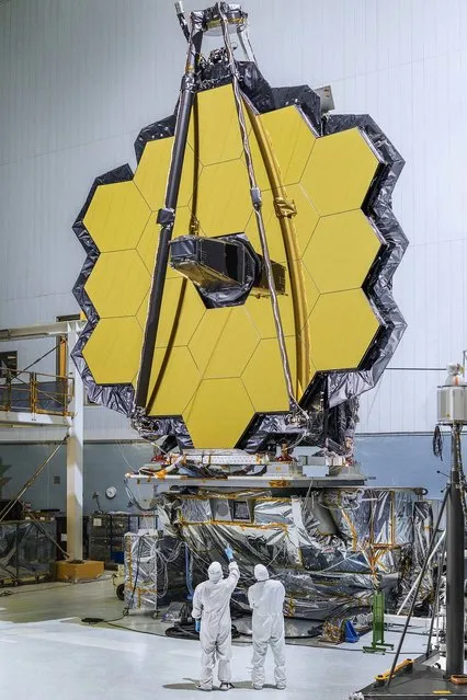 This photo released by NASA on November 2, 2016 shows the primary mirror of NASA' s James Webb Space Telescope consisting of 18 hexagonal mirrors looking like a giant puzzle piece standing in the massive clean room of NASA' s Goddard Space Flight Center in Greenbelt, Maryland. Appropriately, combined with the rest of the observatory, the mirrors will help piece together puzzles scientists have been trying to solve throughout the cosmos. Webb's primary mirror will collect light for the observatory in the scientific quest to better understand our solar system and beyond. Using these mirrors and Webb's infrared vision scientists will peer back over 13.5 billion years to see the first stars and galaxies forming out of the darkness of the early universe. Unprecedented infrared sensitivity will help astronomers to compare the faintest, earliest galaxies to today's grand spirals and ellipticals, helping us to understand how galaxies assemble over billions of years. (Photo by Chris Gunn/AFP Photo/NASA)