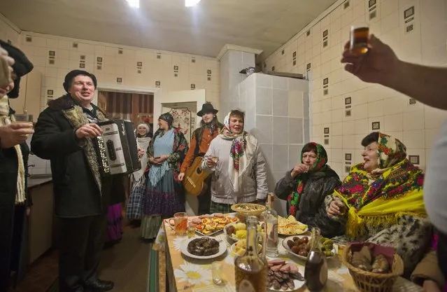People sing Christmas carols, known locally as “Kolyadki”, drink and eat in the village of Noviny, east of the capital Minsk, January 13, 2015. Many Orthodox Belarussians mark the New Year, according to the Julian calendar on January 13. (Photo by Vasily Fedosenko/Reuters)