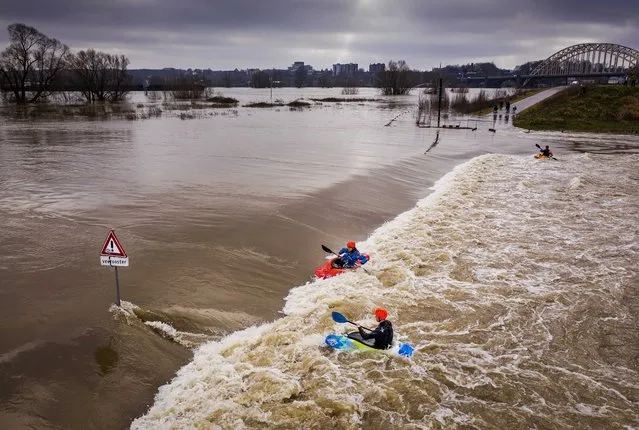 A picture taken with a drones shows Kayakers make use of the current that flows over a dike in the flood plains of the Waal river, with the Waal bridge of Nijmegen in the background in Lent, the Netherlands, 04 February 2021. The heavy rainfall and snow melt in southern Germany has caused a significant rise in the water level in various places in the Netherlands. (Photo by Robin Van Lonkhuijsen/EPA/EFE)