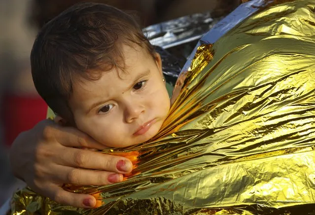A Syrian refugee child is covered by thermal blanket in the port of Kos following a rescue mission off the Greek island August 10, 2015. (Photo by Yannis Behrakis/Reuters)