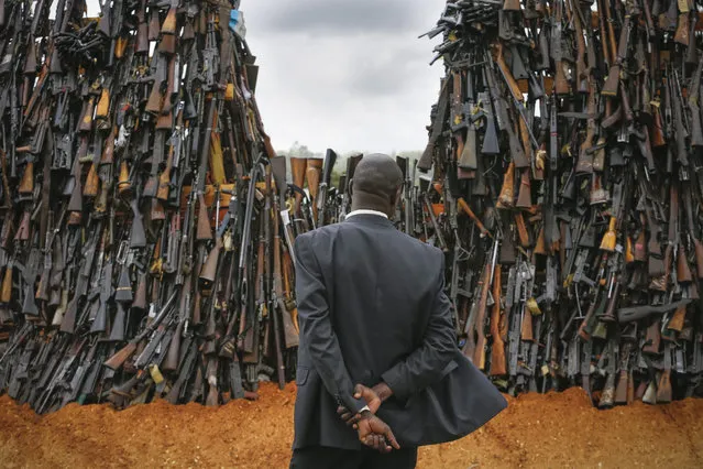 A government official looks at a pile of illegal firearms before it was set alight at a field in Ngong, in the outskirts of the capital Nairobi, Kenya, 15 November 2016. 5,250 illegal firearms were set alight by government in an effort to stem the flow of illicit firearms in the country. Deputy President William Ruto urged civilians in possession of unlicensed guns to surrender them. (Photo by Dai Kurokawa/EPA)