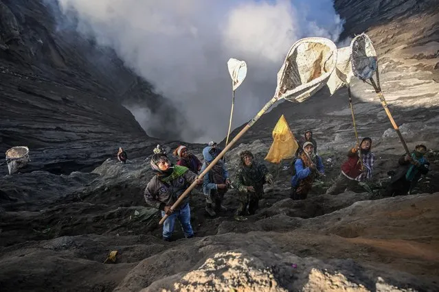 Villagers use nets to catch offerings thrown by members of the Tengger sub-ethnic group in the crater of the active Mount Bromo volcano as part of the Yadnya Kasada festival in Probolinggo, East Java province on June 5, 2023. (Photo by Juni Kriswanto/AFP Photo)