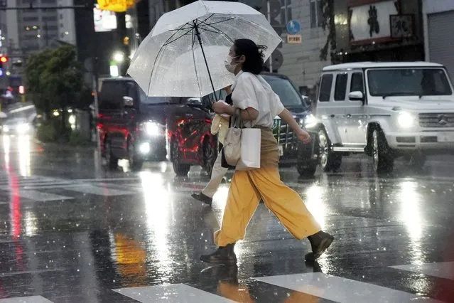 A person holds an umbrella against strong wind and rain as he walks on a street Friday, June 2, 2023, in Kawasaki near Tokyo, as a tropical storm was approaching. (Photo by Eugene Hoshiko/AP Photo)