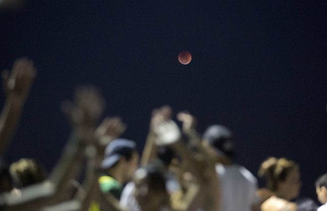A blood moon rises at Arpoador beach in Rio de Janeiro, Brazil, Friday, July 27, 2018. Skywatchers around much of the world are looking forward to a complete lunar eclipse that will be the longest this century, in Rio de Janeiro, Brazil, Friday, July 27, 2018. (Photo by Silvia Izquierdo/AP Photo)