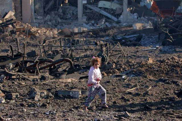 A girl walks over debris at a site hit by one of 3 three truck bombs, in the YPG-controlled town of Tel Tamer, Syria December 11, 2015. (Photo by Rodi Said/Reuters)