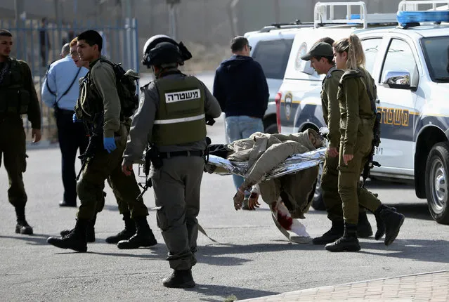 Israeli security forces evacuate the body of a Palestinian who Israeli police said was shot and killed by an Israeli security guard after the Palestinian tried to stab him, at Qalandiya checkpoint near the West Bank city of Ramallah November 22, 2016. (Photo by Mohamad Torokman/Reuters)