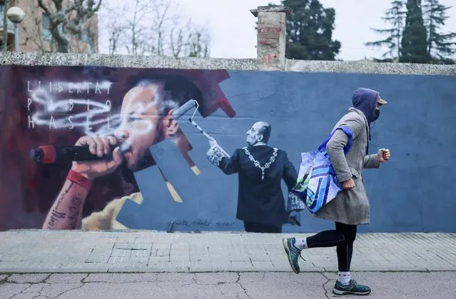 A person walks past a graffiti by Catalan artist Cinta Vidal depicting Spain's former king Juan Carlos and rapper Pablo Hasel in Cardedeu, near Barcelona, Spain on February 15, 2021. The phrase wrote on the wall reads “Freedom for Pablo Hasel”. (Photo by Nacho Doce/Reuters)