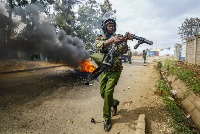 A riot policeman reloads a teargas grenade launcher during clashes with protesters in the Kibera area of Nairobi, Kenya Wednesday, July 19, 2023. Kenyans were back protesting on the streets of the capital Wednesday against newly imposed taxes and the increased cost of living. (Photo by Brian Inganga/AP Photo)