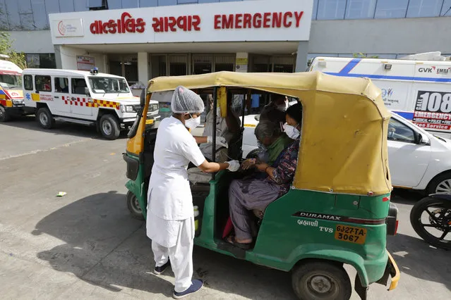 A COVID-19 patient attended by a health worker inside a vehicle at a dedicated COVID-19 government hospital in Ahmedabad, India, Thursday, April 22, 2021. A fire killed 13 COVID-19 patients in a hospital in western India early Friday as an extreme surge in coronavirus infections leaves the nation short of medical care and oxygen. India reported another global record in daily infections for a second straight day Friday, adding 332,730 new cases. The surge already has driven its fragile health systems to the breaking point with understaffed hospitals overflowing with patients and critically short of supplies. (Photo by Ajit Solanki/AP Photo)