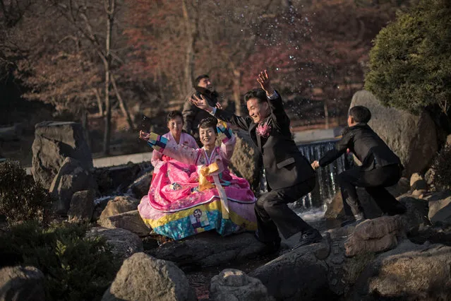 A bride and groom throw water in the air as they pose for photos in a park in Pyongyang on November 25, 2016. (Photo by Ed Jones/AFP Photo)