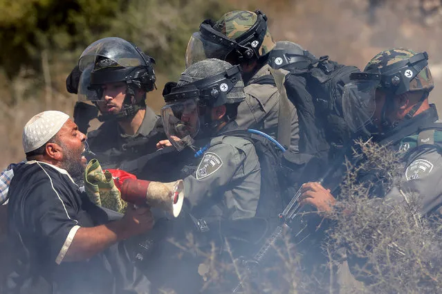A Palestinian man scuffles with Israeli troops during a protest against Israeli land seizures for Jewish settlements, in the village of Ras Karkar, near Ramallah in the occupied West Bank September 14, 2018. (Photo by Mohamad Torokman/Reuters)