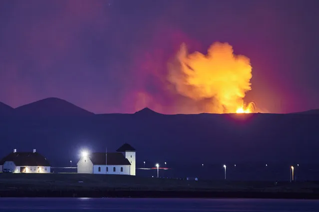 Bessastadir, the official residence of the President of Iceland seen from the  Icelandic capital Reykjavik, is seen with the glow from the lava coming out of a fissure near the Fagradalsfjall on the Reykjanes Peninsula behind, on May 5, 2021. The volcanic eruption on Iceland's Reykjanes peninsula this weekend abruptly became volatile after remarkable stability since it began on 19 March, 2021, cycling between almost completely stopping, and then throwing lava up to 300 metres into the air which is clearly visible in the capital Reykjavik. (Photo by Halldor Kolbeins/AFP Photo)