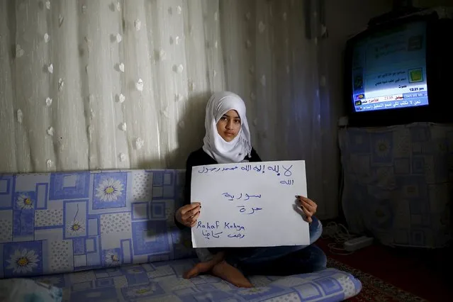 Syrian refugee Rahaf Kahya, 13, holds paper with writing in Arabic that reads: "There is no god only Allah and Muhammad is the messenger of Allah. Free Syria" in Nizip refugee camp in Gaziantep province, Turkey, December 13, 2015. (Photo by Umit Bektas/Reuters)