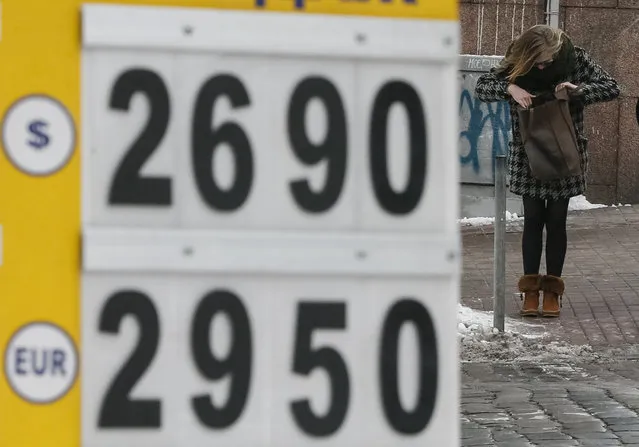 A woman stands near a currency exchange office in Kiev, Ukraine, January 19, 2016. The average rate of Ukraine's hryvnia currency weakened to a 10-month low of 24.93 to the dollar on Tuesday, central bank data showed. (Photo by Gleb Garanich/Reuters)
