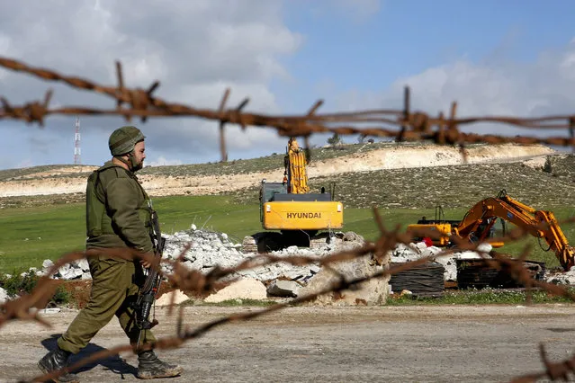 Israeli border policemen stand guard during the demolition of a house owned by the Palestinian Salem Abu Ayyash in the West Bank town of Dura, south of Hebron, 20 January 2016. Israel claims the home was built without the necessary permits which is located in area an under the Israeli adminstrative control. (Photo by Abed Al Hashlamoun/EPA)