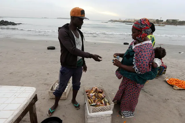 A woman counts money at the beach fish market opposite Dakar boat island, Senegal  December 18, 2016. (Photo by Afolabi Sotunde/Reuters)