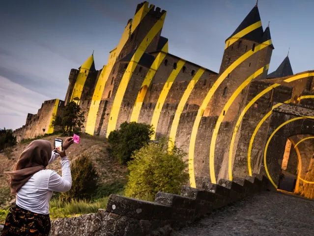 “Art installation by Felice Varini on the medieval walls of Carcassonne, France. At sunset there was a crowd of people where the concentric circles aligned. I was intrigued by this lady sending a hand-written message on a pink Post-it note”. (Photo by Katy Bridgestock/The Guardian)