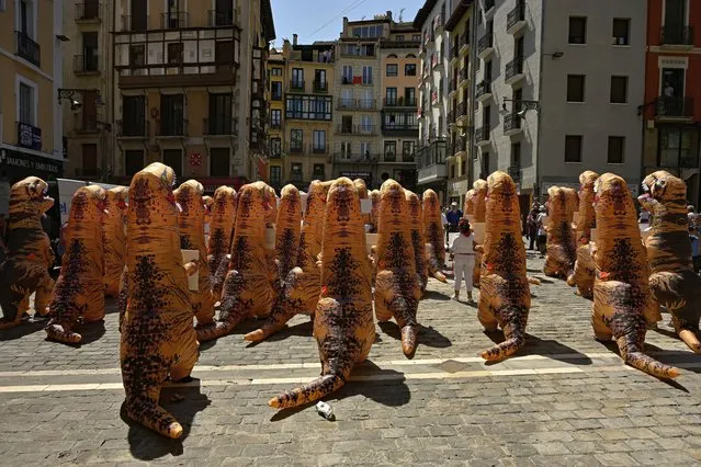 People dressing as dinosaurs protest against animal cruelty before the start of the San Fermin festival, which has been cancelled for the last two years due to coronavirus restrictions, in Pamplona, northern Spain, Tuesday, July 5, 2022. People from around the world flock to Pamplona to take part in the nine days of the festival which starts on Wednesday, July 6. (Photo by Alvaro Barrientos/AP Photo)