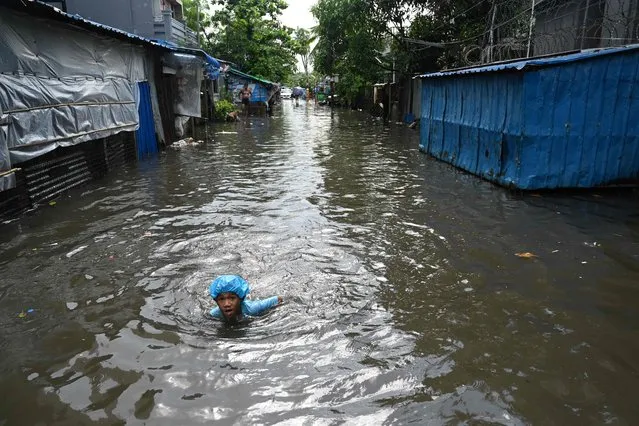 A boy swims through flood waters after heavy rain in Yangon on June 28, 2023. (Photo by Sai Aung Main/AFP Photo)