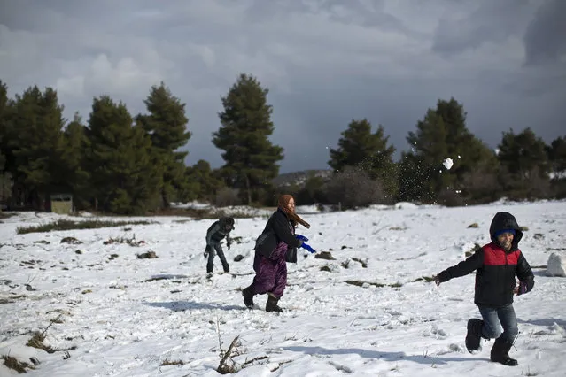 A Syrian refugee woman throws a snowball while she and others play at the refugee camp of Ritsona about 86 kilometers (53 miles) north of Athens, Friday, December 30, 2016. Over 62,000 refugees and migrants are stranded in Greece after a series of Balkan border closures and an European Union deal with Turkey to stop migrant flows. (Photo by Muhammed Muheisen/AP Photo)