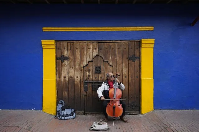 Fabio Guarin, 76, plays a cello for tips which he said he uses to buy his meals in the La Candelaria neighborhood of Bogota, Colombia, Thursday, August 4, 2022. Guarin said he used to earn money playing in an amateur band known as a “toque”, hired for bars and private events. (Photo by Fernando Vergara/AP Photo)