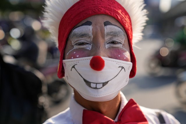 A clown from a group called “Aku Badut Indonesia” or “I am an Indonesian Clown” looks on during an awareness campaign calling for people to always wear their masks to help curb the spread of coronavirus, at a busy intersection in Jakarta, Indonesia, Monday, July 12, 2021. The world's fourth most populous country is battling an explosion of COVID-19 cases that have strained hospitals on the main island of Java. (Photo by Dita Alangkara/AP Photo)
