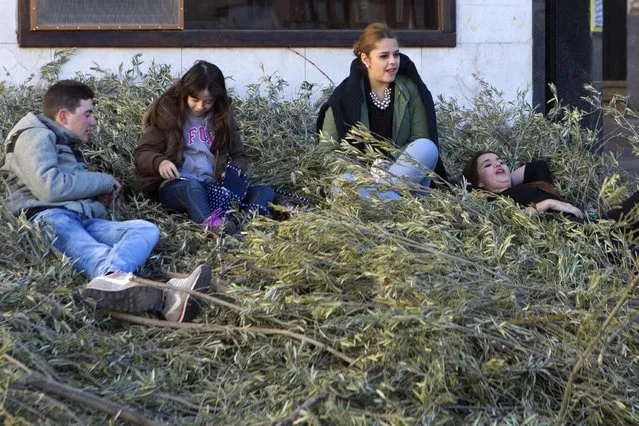 Youths sit of a pile of tree branches to be burned with a cross being erected in the village square in Tielmes, Spain on Easter Sunday Sunday, April 5, 2015 marking the end of Holy week. (Photo by Paul White/AP Photo)