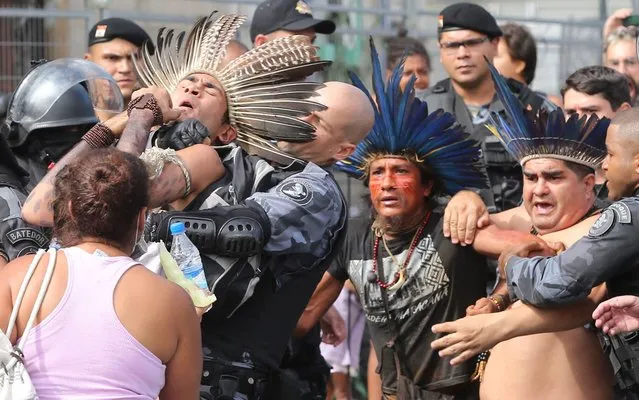 Police officers arrest protestors wearing traditional headdresses outside the Indian Museum, during a protest in Rio de Janeiro, on December 16, 2013. Police arrested more than 20 indigenous people whose Sunday occupation at the abandoned museum, near the Maracana stadium, was a protest against its demolition, which occurred as part of renovations ahead of Brazil’s 2014 World Cup. (Photo by Fabio Motta/Estadão Conteúdo)