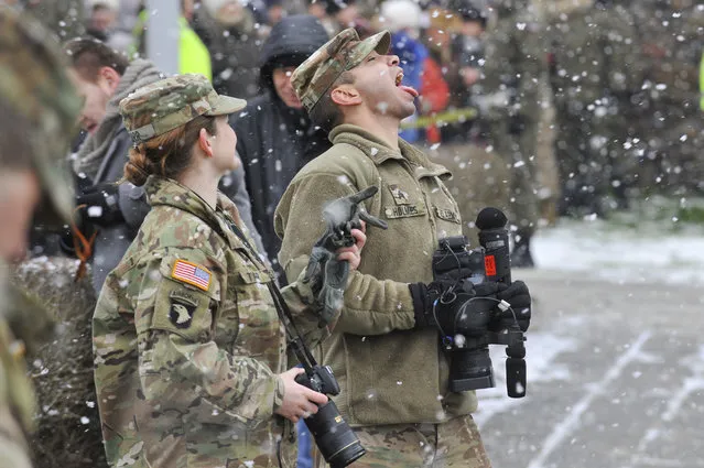 A U.S. Army soldier plays with falling snow during the official welcoming ceremony of the U.S. troops in Zagan, Poland, Saturday, January 14, 2017. The ceremony comes 23 years after the last Soviet troops left Poland and also marks a new historic moment – the first time any Western forces are being deployed on a continuous basis to NATO's eastern flank. (Photo by Krzysztof Zatycki/AP Photo)