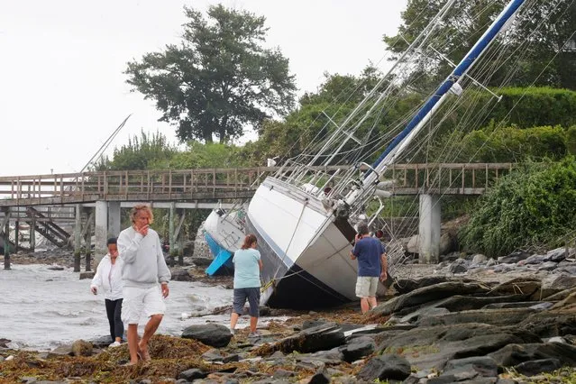 People walk past sailboats that came loose from their moorings and washed ashore during Tropical Storm Henri in Jamestown, Rhode Island, U.S., August 22, 2021. (Photo by Brian Snyder/Reuters)