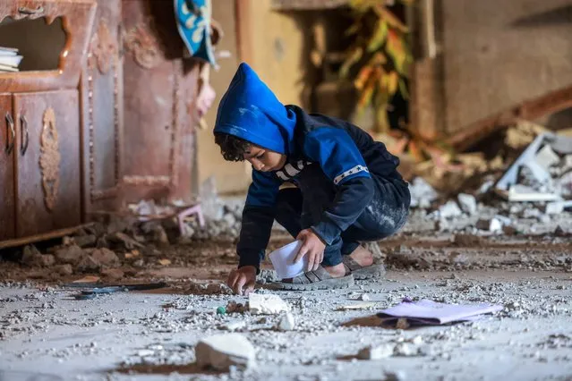 A Palestinian boy collects small pieces of debris following Israeli bombardment in Rafah in the southern Gaza Strip on December 22, 2023, amid continuing battles between Israel and the militant group Hamas. (Photo by Mohammed Abed/AFP Photo)
