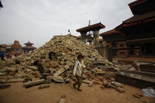 A Nepalese woman walks past a collapsed temple in Bhaktapur Durbar Square after an earthquake in Kathmandu, Nepal, Sunday, April 26, 2015. (Photo by Niranjan Shrestha/AP Photo)