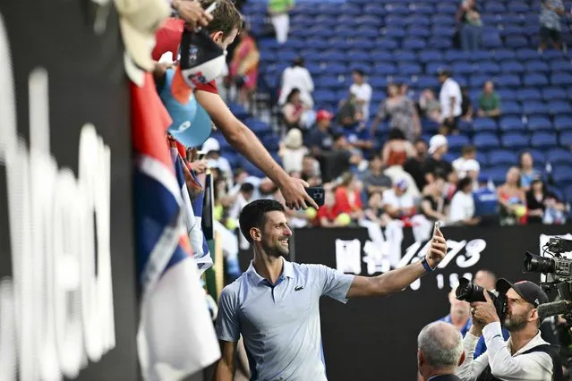 Serbia's Novak Djokovic poses for selfies with fans after his victory against USA's Taylor Fritz in their men's singles quarter-final match on day 10 of the Australian Open tennis tournament in Melbourne on January 23, 2024. (Photo by Paul Crock/AFP Photo)