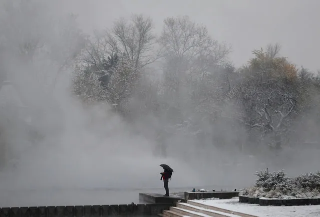 A man stands at the snow-covered City Park during the first snowfall in Budapest, Hungary on November 30, 2023. (Photo by Bernadett Szabo/Reuters)