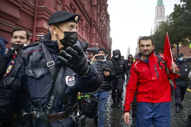 Police escort a demonstrator with a red flag during a protest against the results of the Parliamentary election near Red Square in Moscow, Russia, Saturday, September 25, 2021. The Communist Party has called for a rally in Moscow on Saturday and was urged by the authorities Friday to remove the announcements from its website, otherwise it would be blocked – pressure that a party with seats in the parliament and which backs many of the Kremlin's policies has rarely faced before. (Photo by Vasily Krestyaninov/AP Photo)