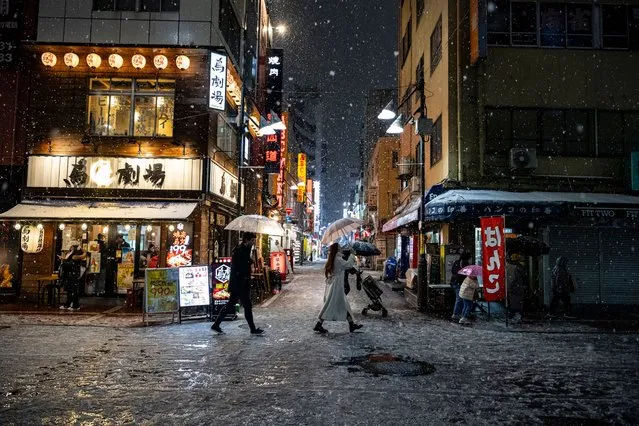 People are walking through a deserted bar area with umbrellas in heavy snow in Tokyo, Japan, on February 5, 2024. (Photo by Yusuke Harada/NurPhoto via Getty Images)