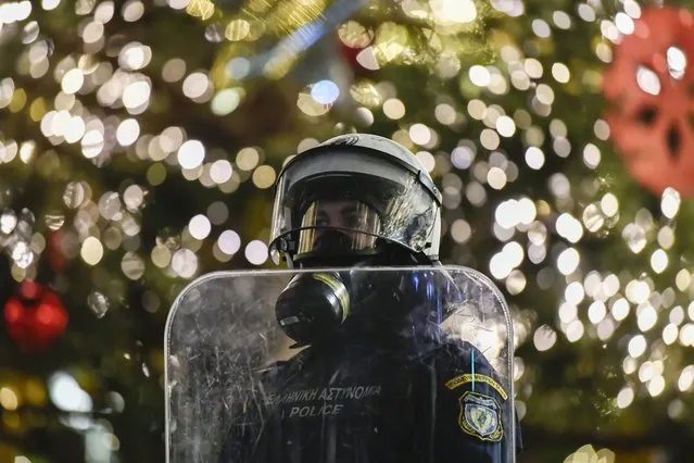 A riot policeman stands guard in front of a Christmas tree in Syntagma square during the 14th anniversary of the fatal shooting by the police of 15-year old Alexis Grigoropoulos, in Athens, on Tuesday, December 6, 2022. A 34-year-old police officer appeared in court over the shooting early Monday of a 16-year-old Roma boy who allegedly drove off from a gas station without paying the bill. Before Monday's incident, protest marches already were planned to mark the anniversary of the 2008 fatal police shooting of a teenager in Athens that sparked Greece’s worst riots in decades. (Photo by Michael Varaklas/AP Photo)