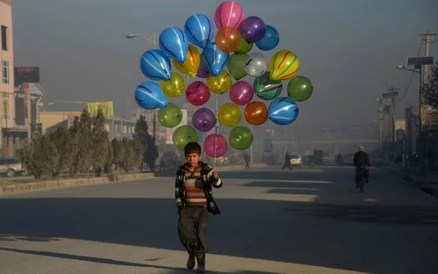 Afghan boy Hizbullah, 10, walks as he looks for customers to buy his balloons on the streets of Mazar-i-Sharif on February 3, 2016. (Photo by Farshad Usyan/AFP Photo)