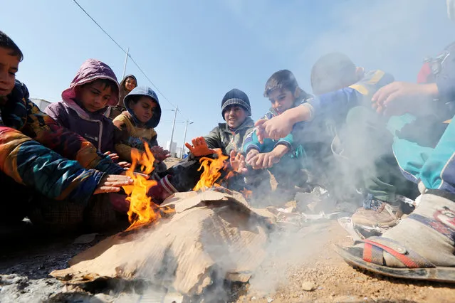 Displaced Iraqi children get warm up by a fire at Khazer camp, Iraq February 1, 2017. (Photo by Ahmed Saad/Reuters)