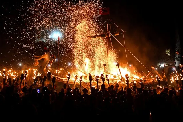 Members of the Up Helly Aa “Jarl Squad” set fire on ship during a parade through the streets of in Lerwick, Shetland Islands on January 30, 2024 during the Up Helly Aa festival later in the day. Up Helly Aa celebrates the influence of the Scandinavian Vikings in the Shetland Islands and culminates with up to 1,000 “guizers” (men in costume) throwing flaming torches into their Viking longboat and setting it alight later in the evening. (Photo by Andy Buchanan/AFP Photo)