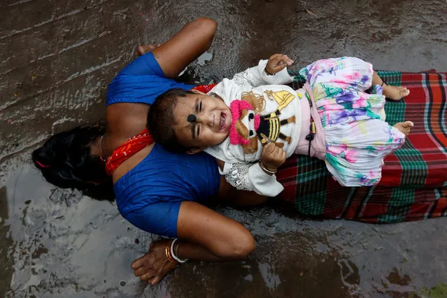 An infant lies on the back of a woman as she performs a ritual while worshipping Sheetala Mata, the Hindu goddess of smallpox, during Sheetala Puja in which devotees pray for the betterment of their family and society, in Kolkata, India, March 28, 2019. (Photo by Rupak De Chowdhuri/Reuters)